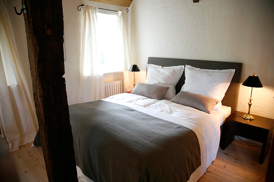 Modernes Doppelbett in rustikaler Architektur mit Holzbalken in der Reetdach-Fewo Harms-Hoff in Hanstedt-Schierhorn